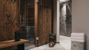 A modern bathroom with a wooden wall, a stone shower, and a bench with a vase.