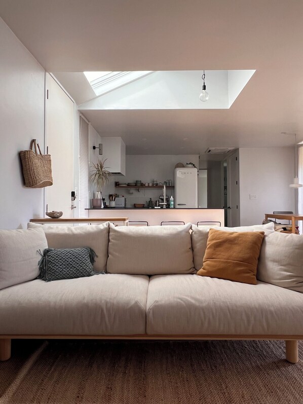 A modern living room with a sofa, a hanging basket, and a skylight.