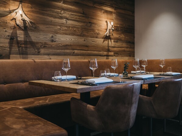 A restaurant with a wooden wall, leather seating, and a table set for dining.