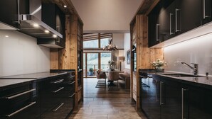 Een moderne keuken met donkere kastjes, een centraal eiland en uitzicht op een eetgedeelte.