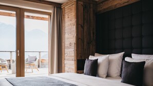 Een slaapkamer met een groot bed, een houten hoofdbord en uitzicht op de omgeving via een schuifdeur.