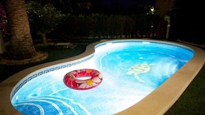 En swimmingpool med flisekant og et cirkulært område med jacuzzi.