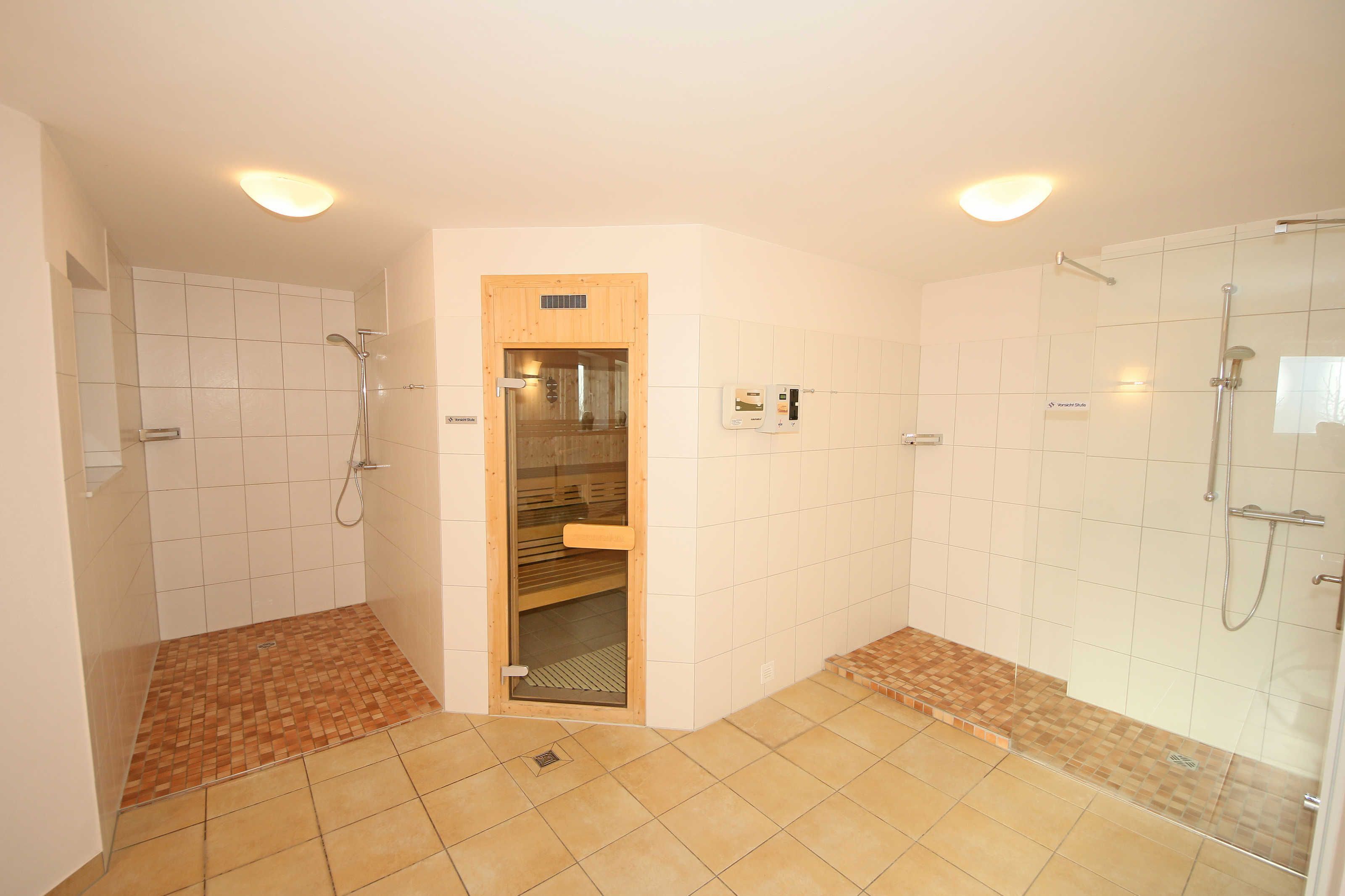 Ein Badezimmer mit zwei Duschbereichen, einer Holztür und Fliesenböden.