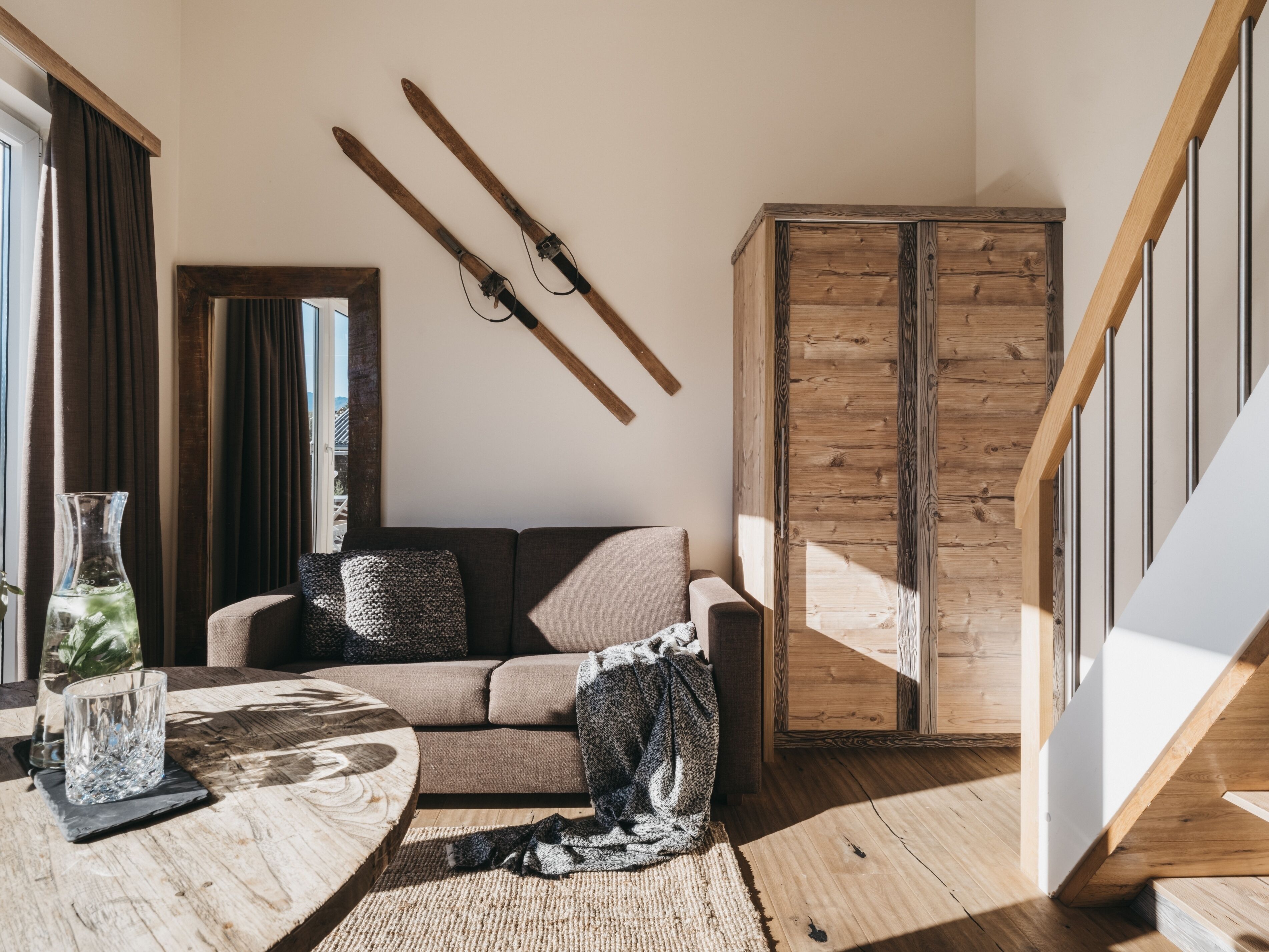 A modern living room with a wooden floor, a sofa, a coffee table, and a large wooden cabinet.