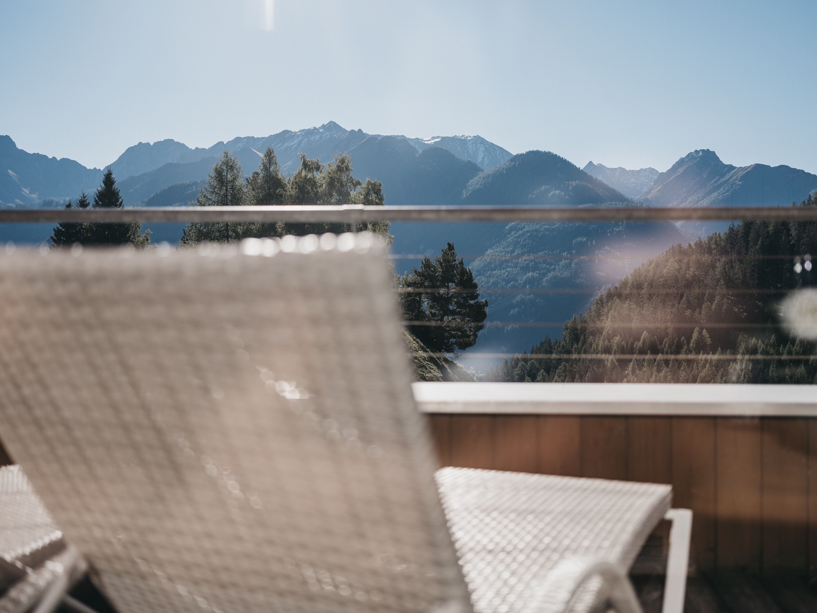 A lounge chair overlooking a lake with mountains in the background.