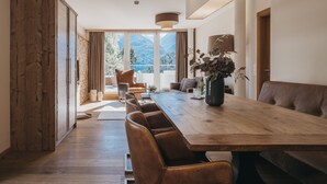 A modern dining area with a long wooden table, leather chairs, and a vase with flowers. - VAYA Terrazena Serfaus (Serfaus)