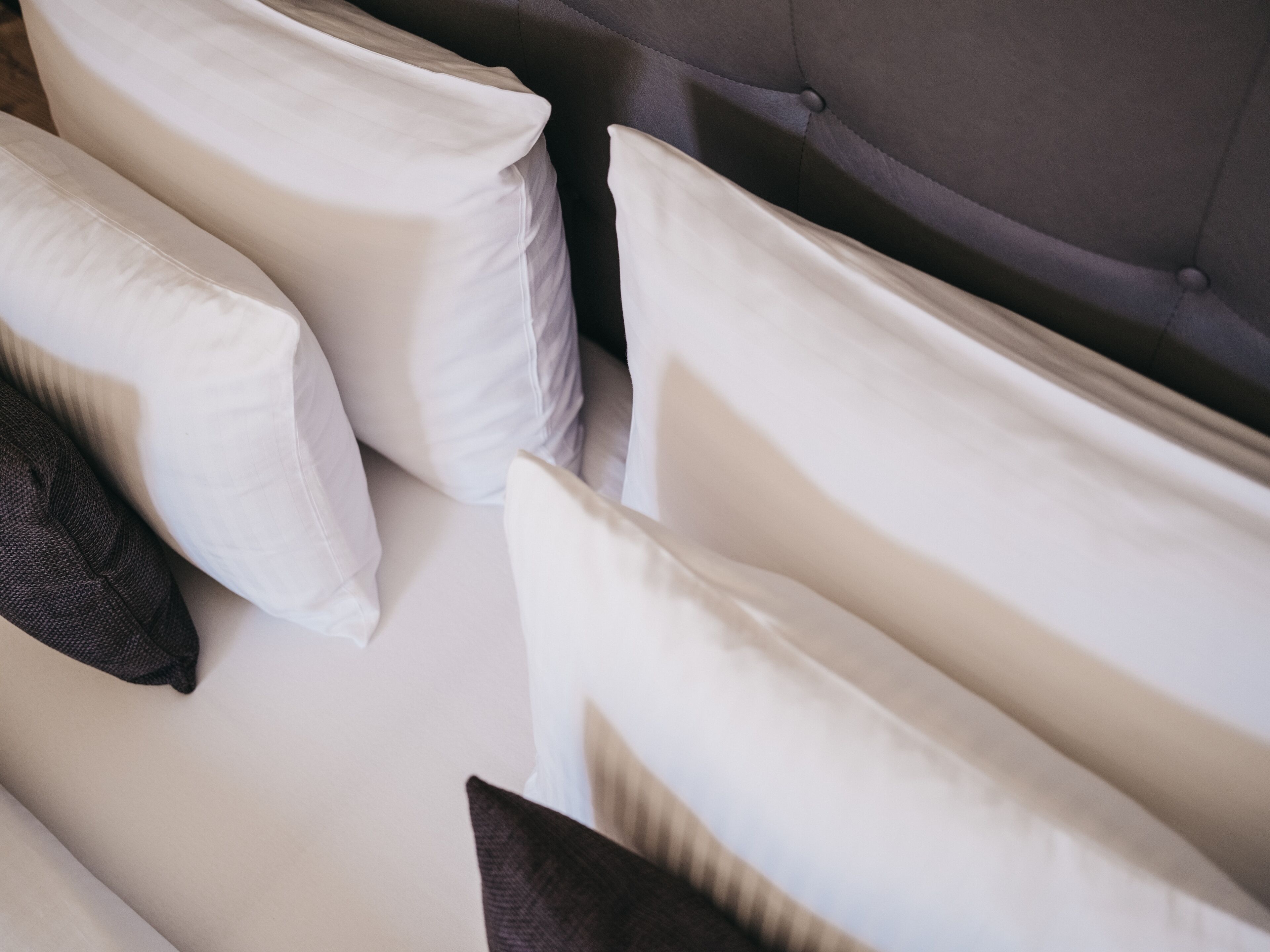 A bed with multiple pillows, including white and dark-colored ones.