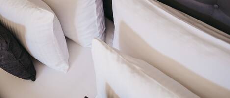 A bed with multiple pillows, including white and dark-colored ones.