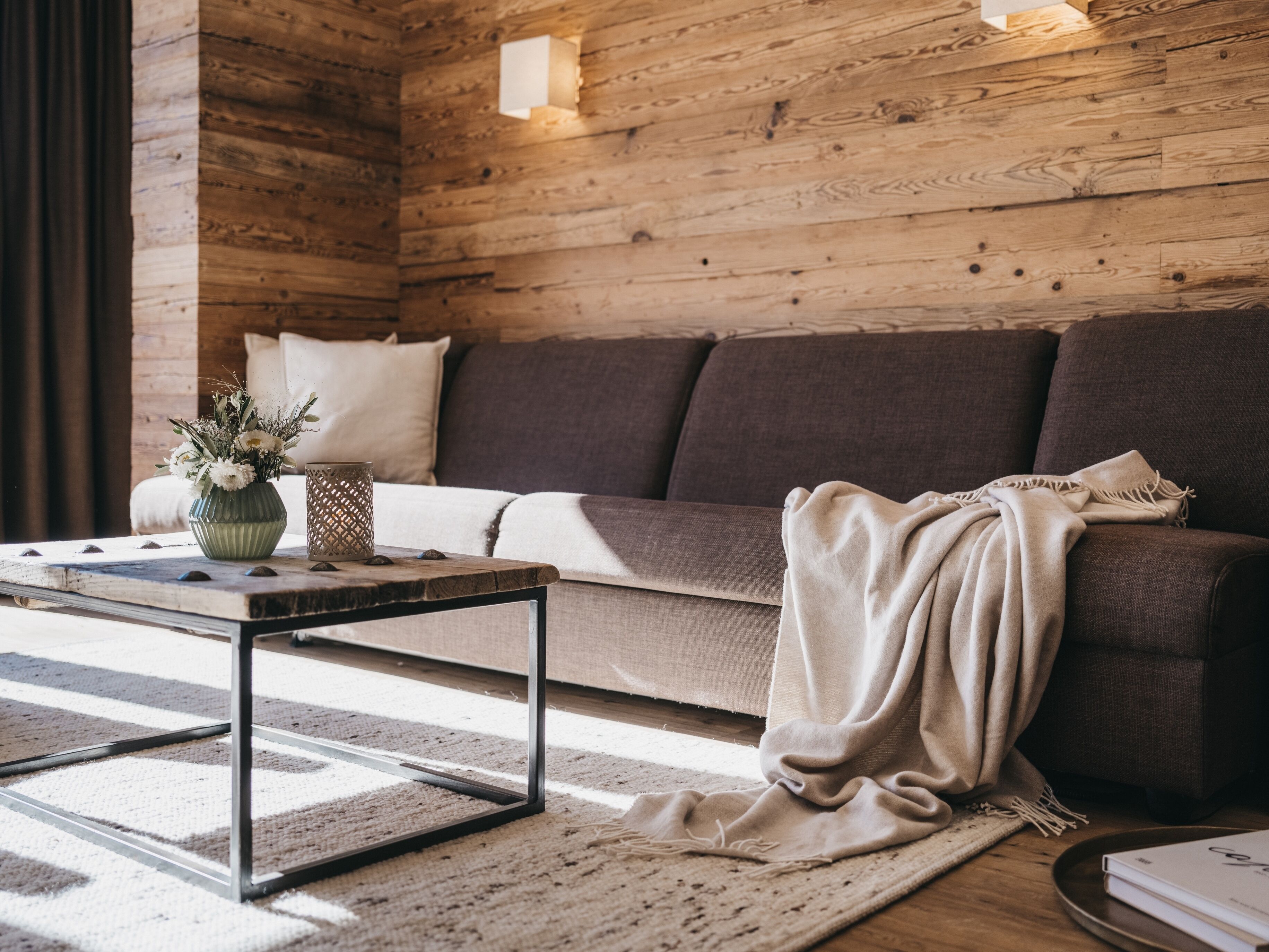 Ein gemütliches Wohnzimmer mit Holzwand, einer Couch, einem Couchtisch und einem Teppich.