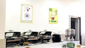 Montaje tipo bufé con varias estaciones de autoservicio, una máquina de café y un refrigerador.