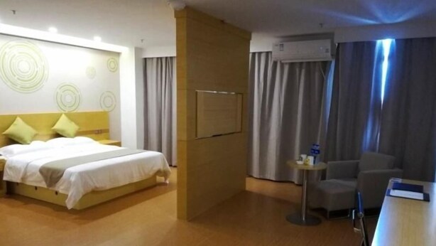 Una habitación de hotel con cama, escritorio, silla y televisor montado en la pared.