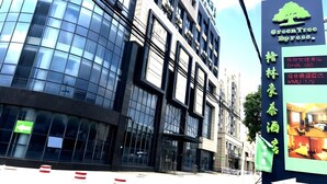 Un edificio moderno con ventanas de vidrio reflectante y un cartel para el hotel GreenTree Express.