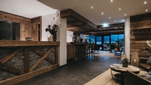 Um interior moderno com parede em pedra, vigas de madeira e um espaço para bar.