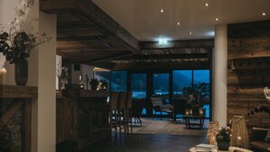 Interior moderno com área de bar, assentos e grandes janelas com vista para o exterior.
