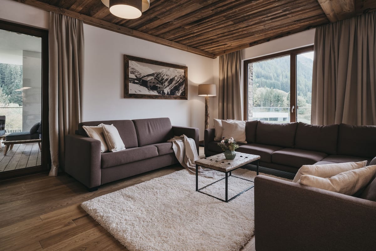 A modern living room with a wooden ceiling, two sofas, a coffee table, and a painting on the wall.