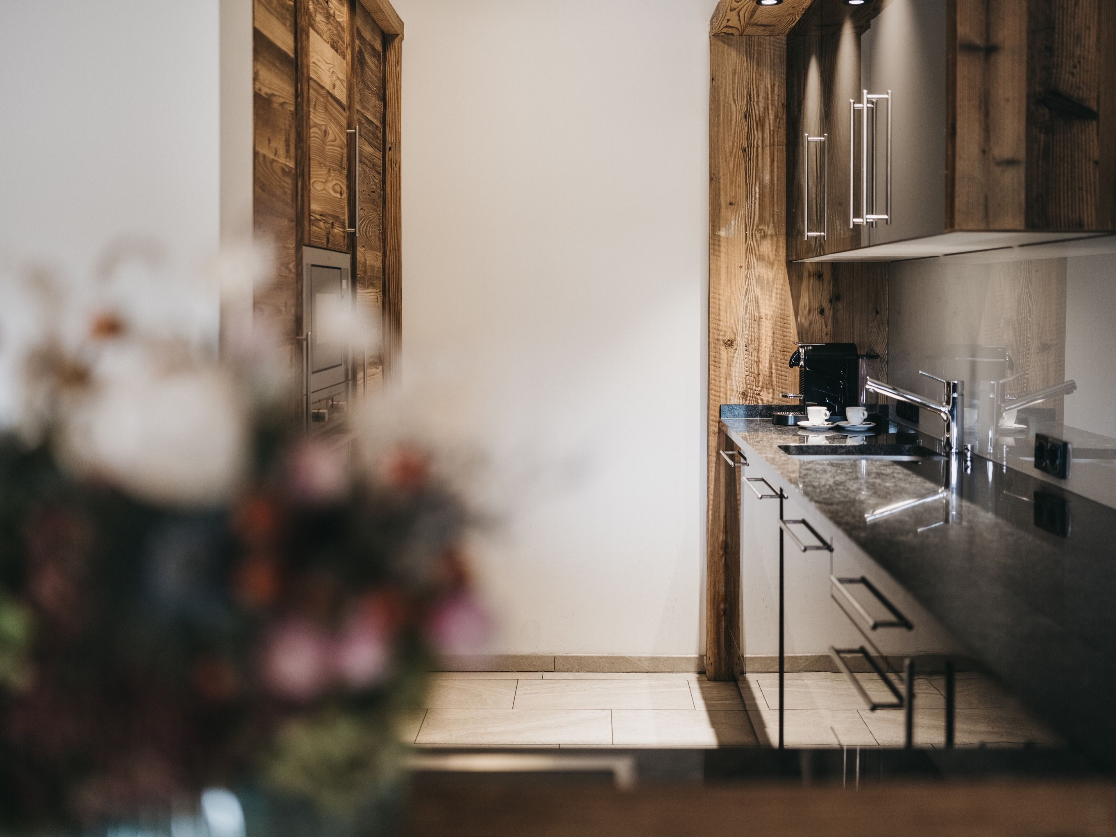 Een moderne keuken met houten kastjes, roestvrijstalen apparatuur en een marmeren aanrecht.
