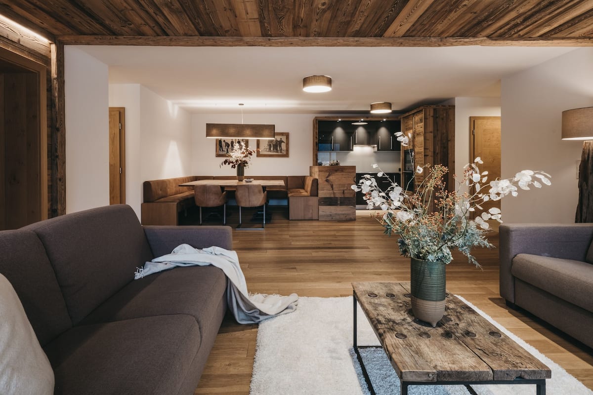 A modern living room with a wooden ceiling, a dining area, and a kitchen.