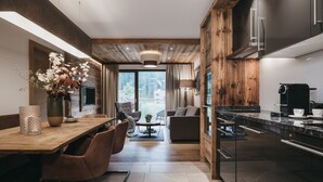 Uma cozinha moderna com uma parede de destaque em madeira, uma área de refeições com mesa e cadeiras, e vista para o exterior.