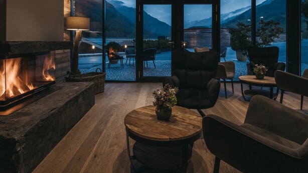 Um interior acolhedor com lareira, assentos confortáveis e grandes janelas com vista para as montanhas.