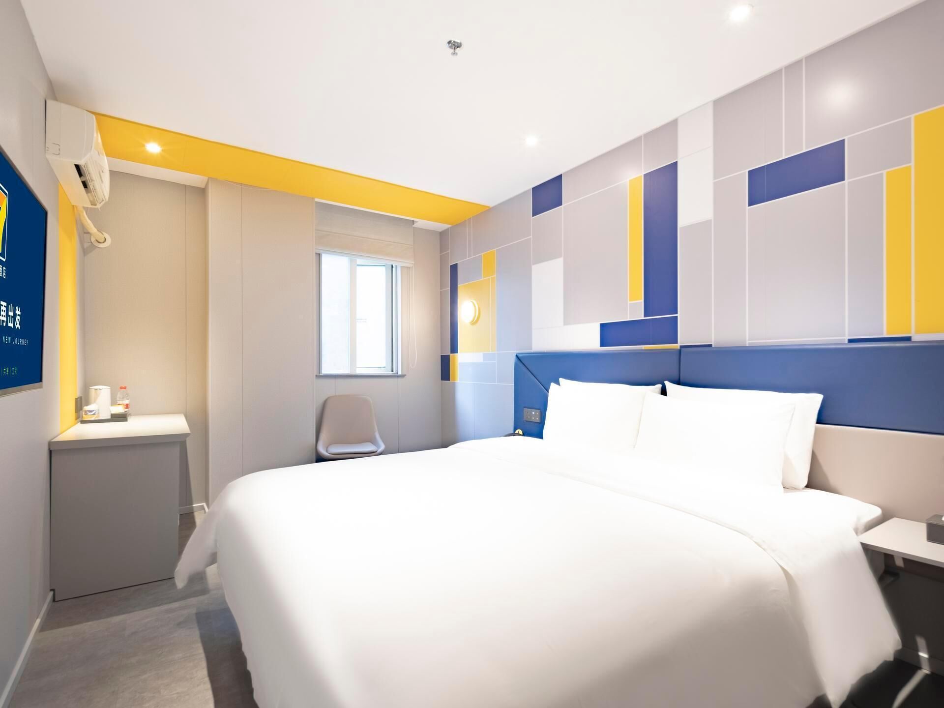 Una habitación de hotel con cama, mesita de noche, silla y ventana.