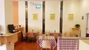 A restaurant with checkered tablecloths, a counter with a computer, and yellow informational posters on the wall.