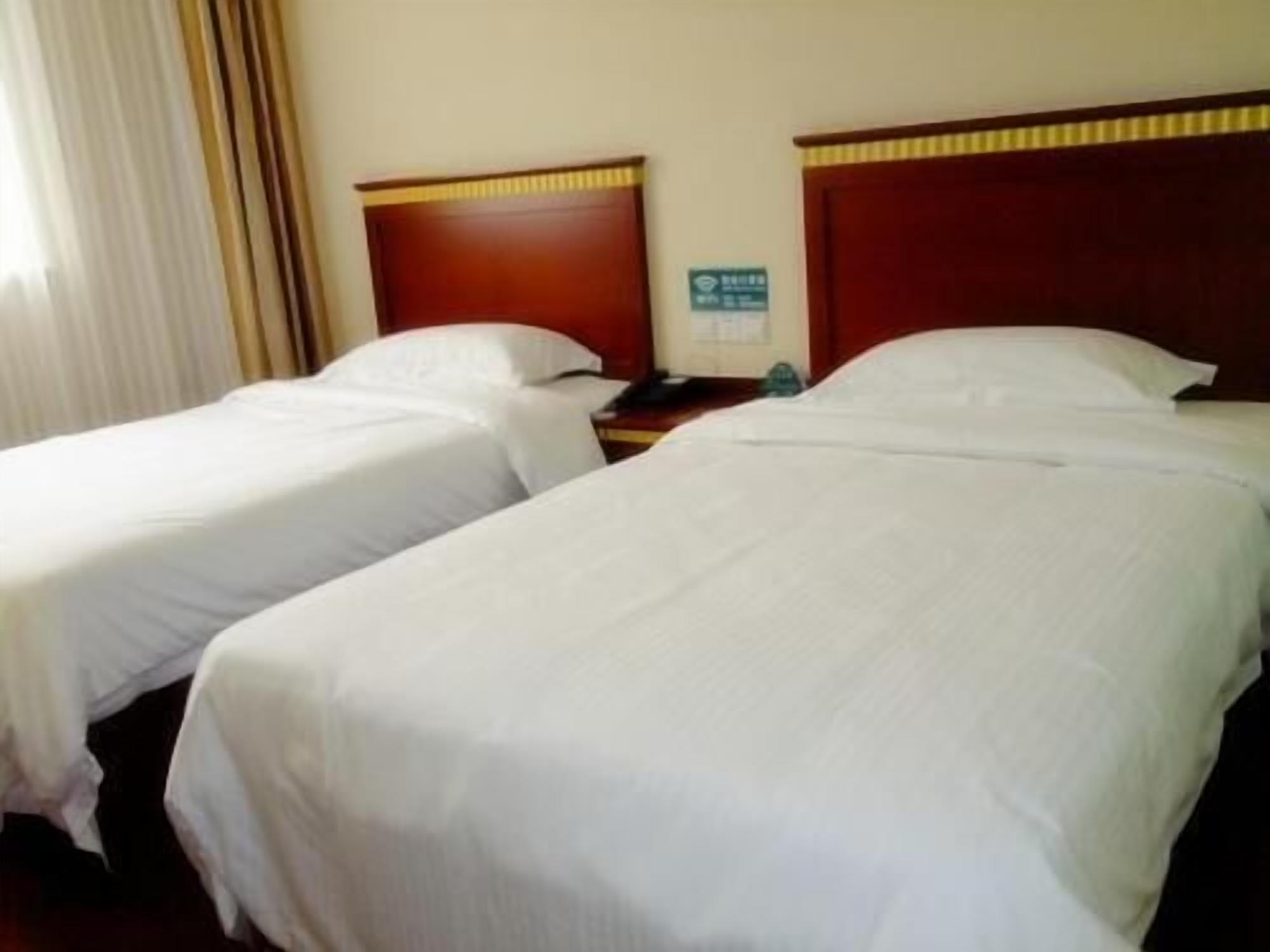 Two single beds with wooden headboards, a nightstand, and a wall-mounted sign.