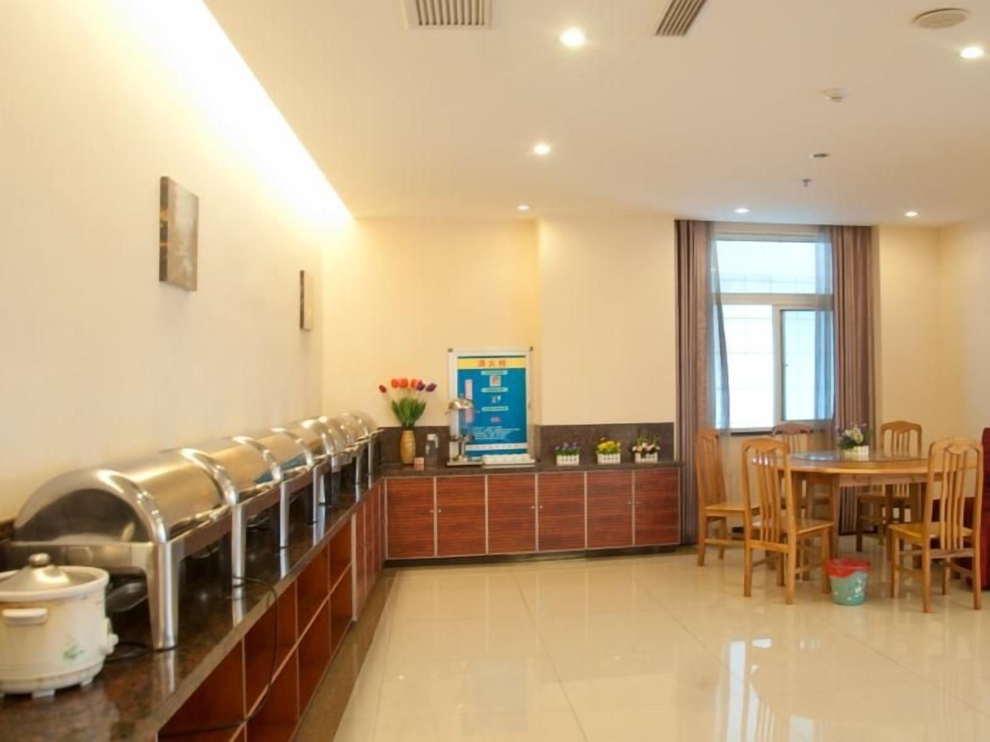 Un espace de restauration d’hôtel avec un buffet, un comptoir de réception et une table à manger avec des chaises.