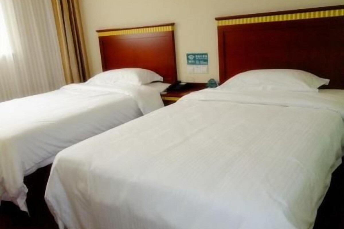 Two single beds with wooden headboards, a nightstand, and a wall-mounted sign.
