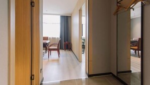A hotel corridor with a wooden door, a dining area with a table and chairs, and a large mirror on the right wall. - Greentree Inn Anhui Xuancheng South Zhaoting Road Business Hotel (Xuancheng)