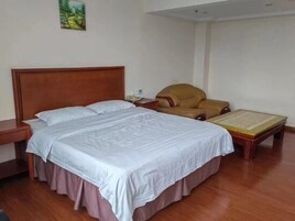 Un dormitorio con una cama de madera, una mesita de noche, una silla y una mesa con un libro.
