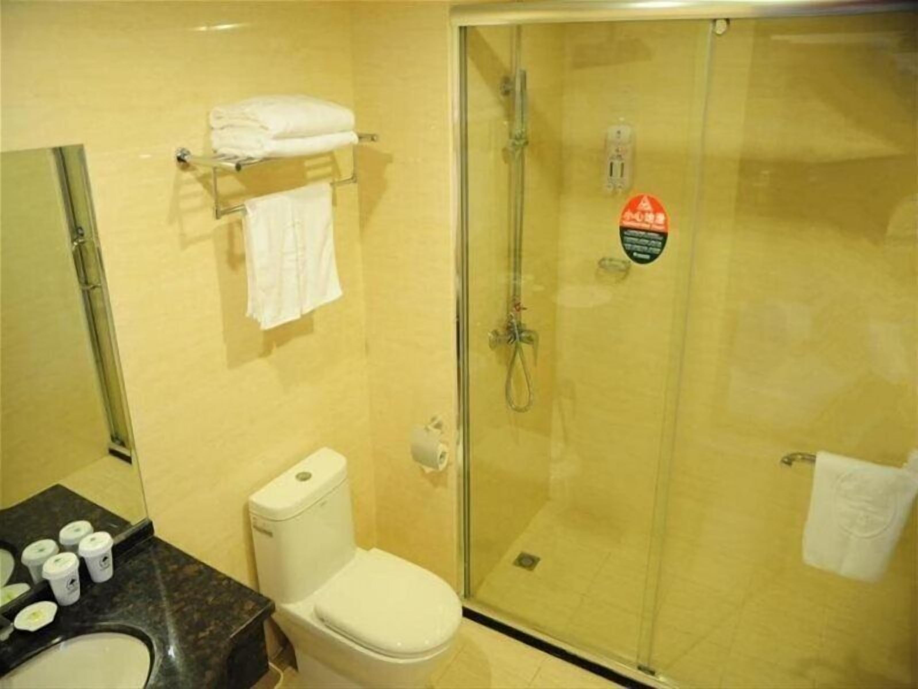 A bathroom with a toilet, a glass-enclosed shower, and a towel rack with towels.