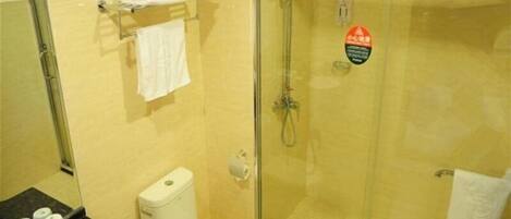 A bathroom with a toilet, a glass-enclosed shower, and a towel rack with towels.