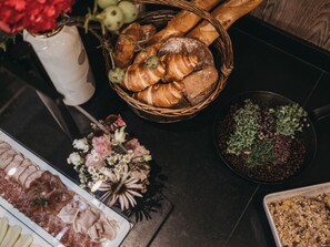 A table with various food items including bread, pastries, and a charcuterie board. - VAYA Galtür Paznaun (Galtur)