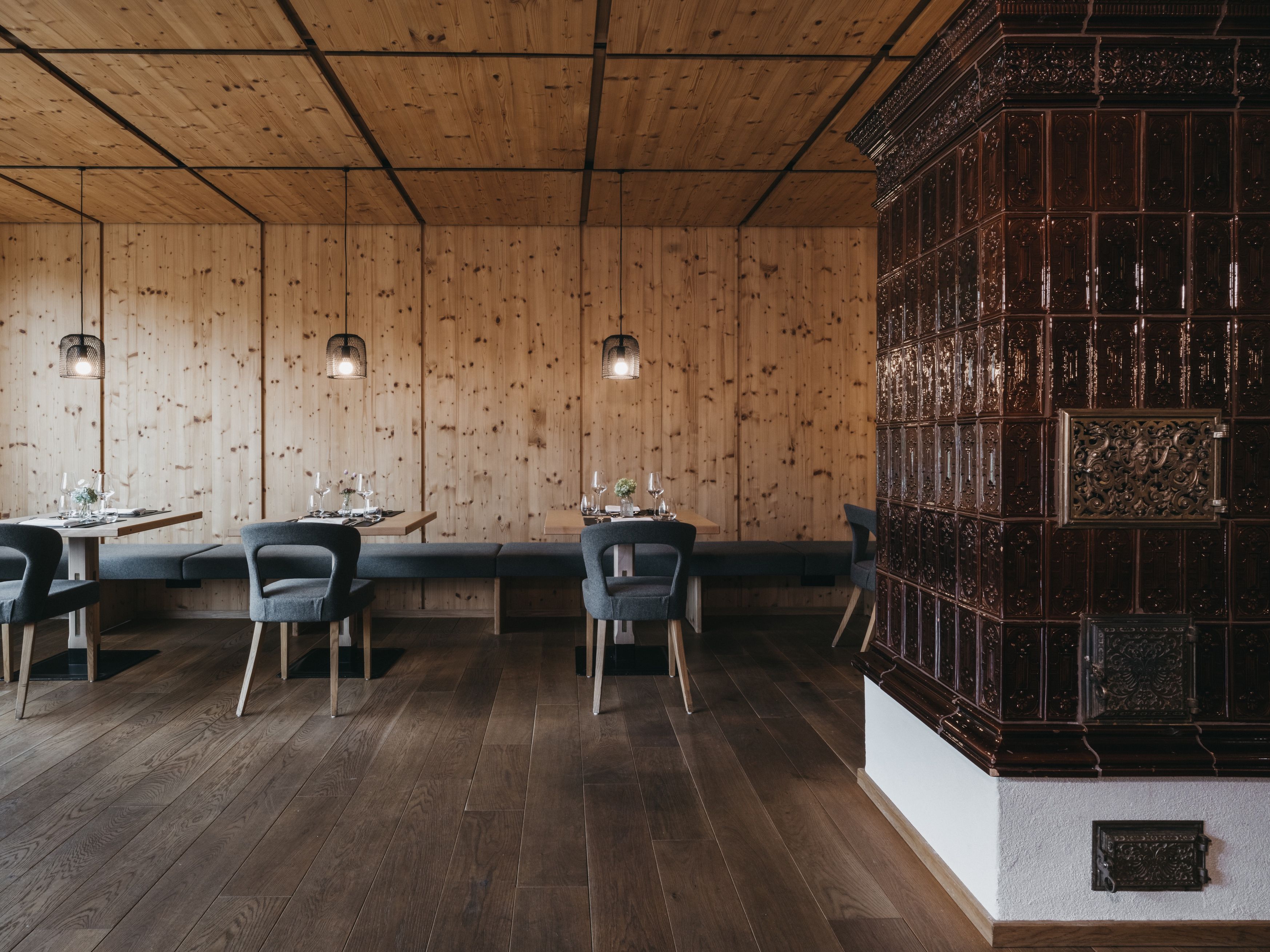 Interior de restaurante com paredes de madeira, piso escuro e painel decorativo de madeira à direita.