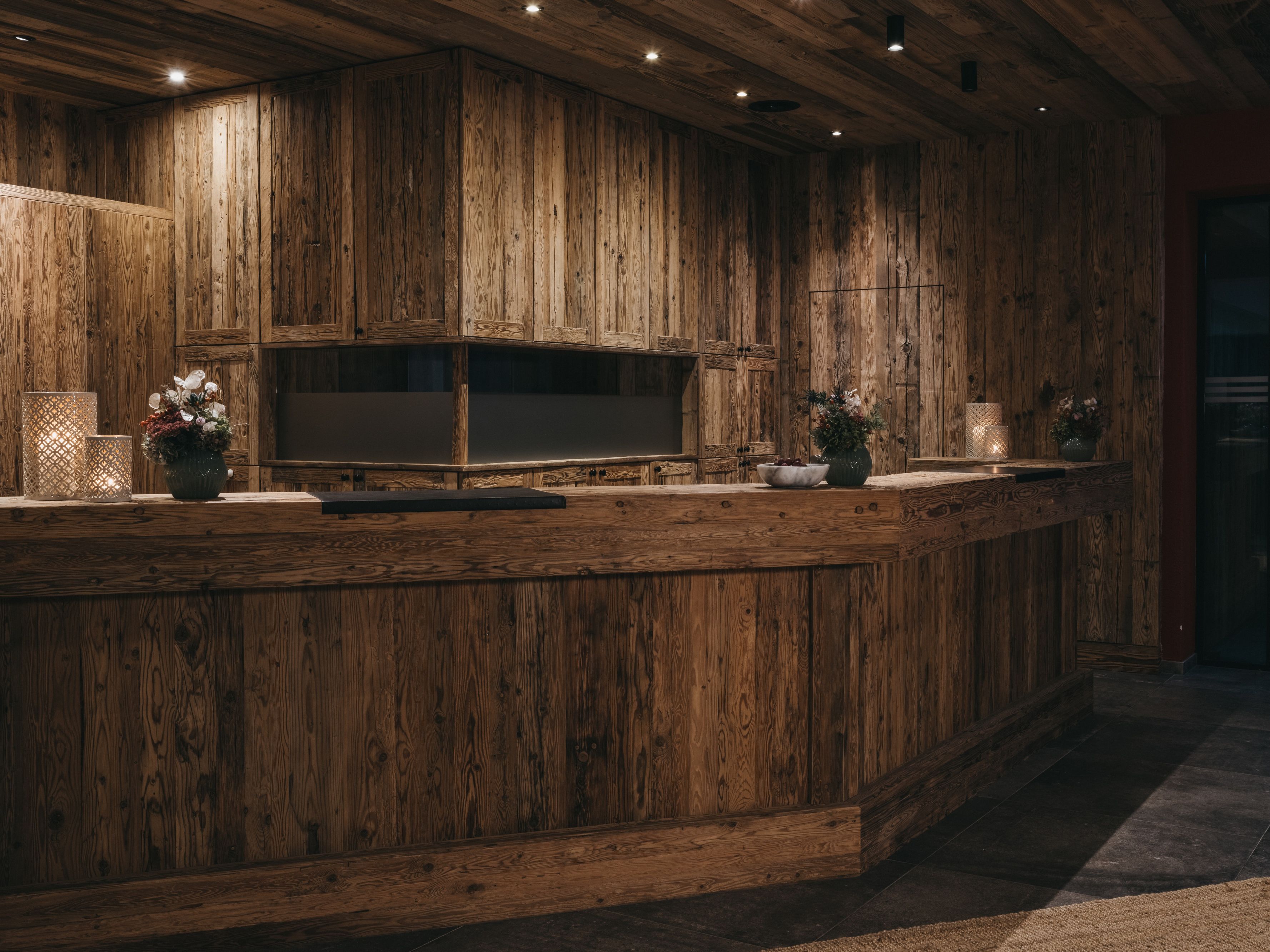 Un intérieur en bois avec un téléviseur encastré, des vases décoratifs et un mur à texture.