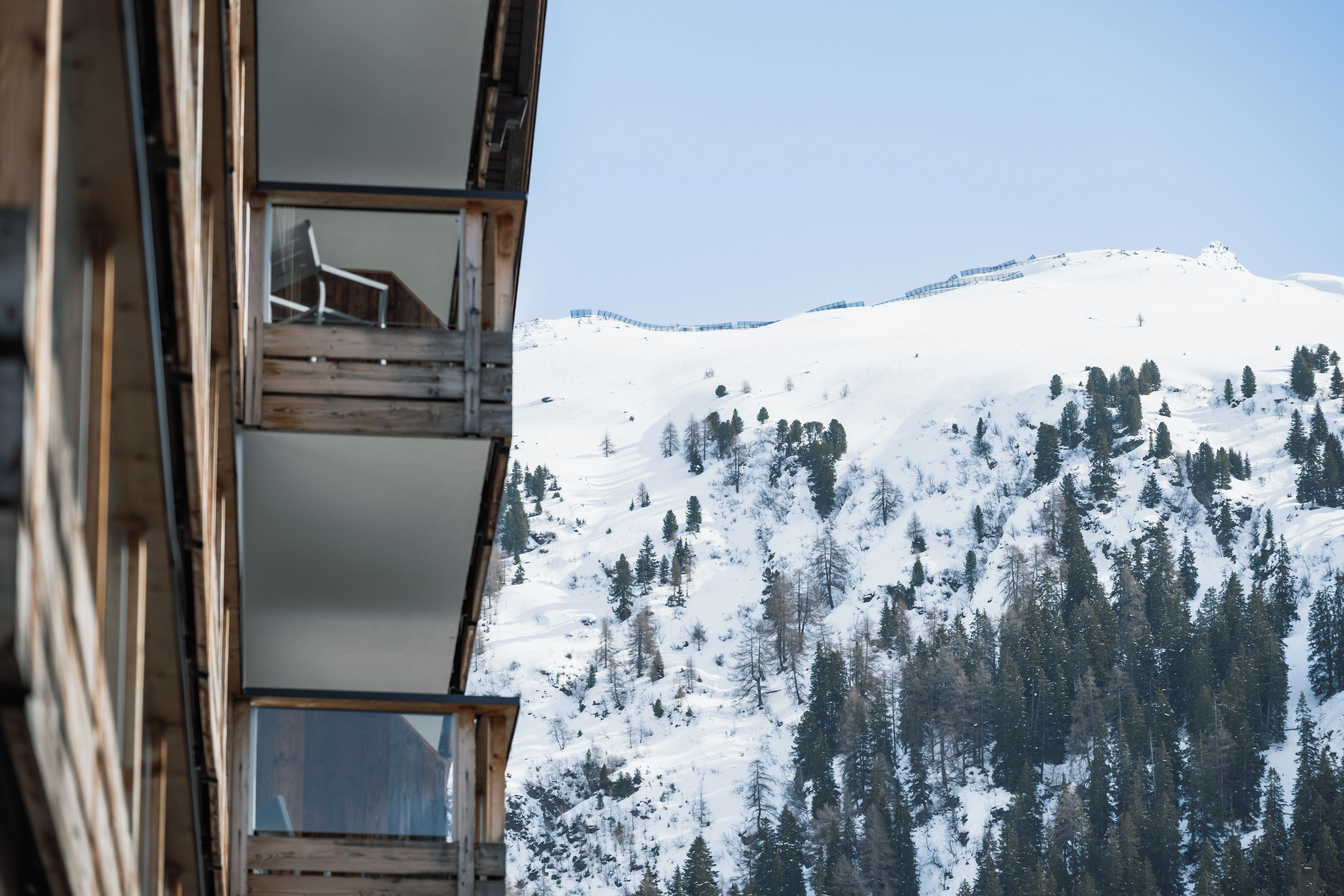 A wooden building with balconies overlooking a snow-covered mountain.