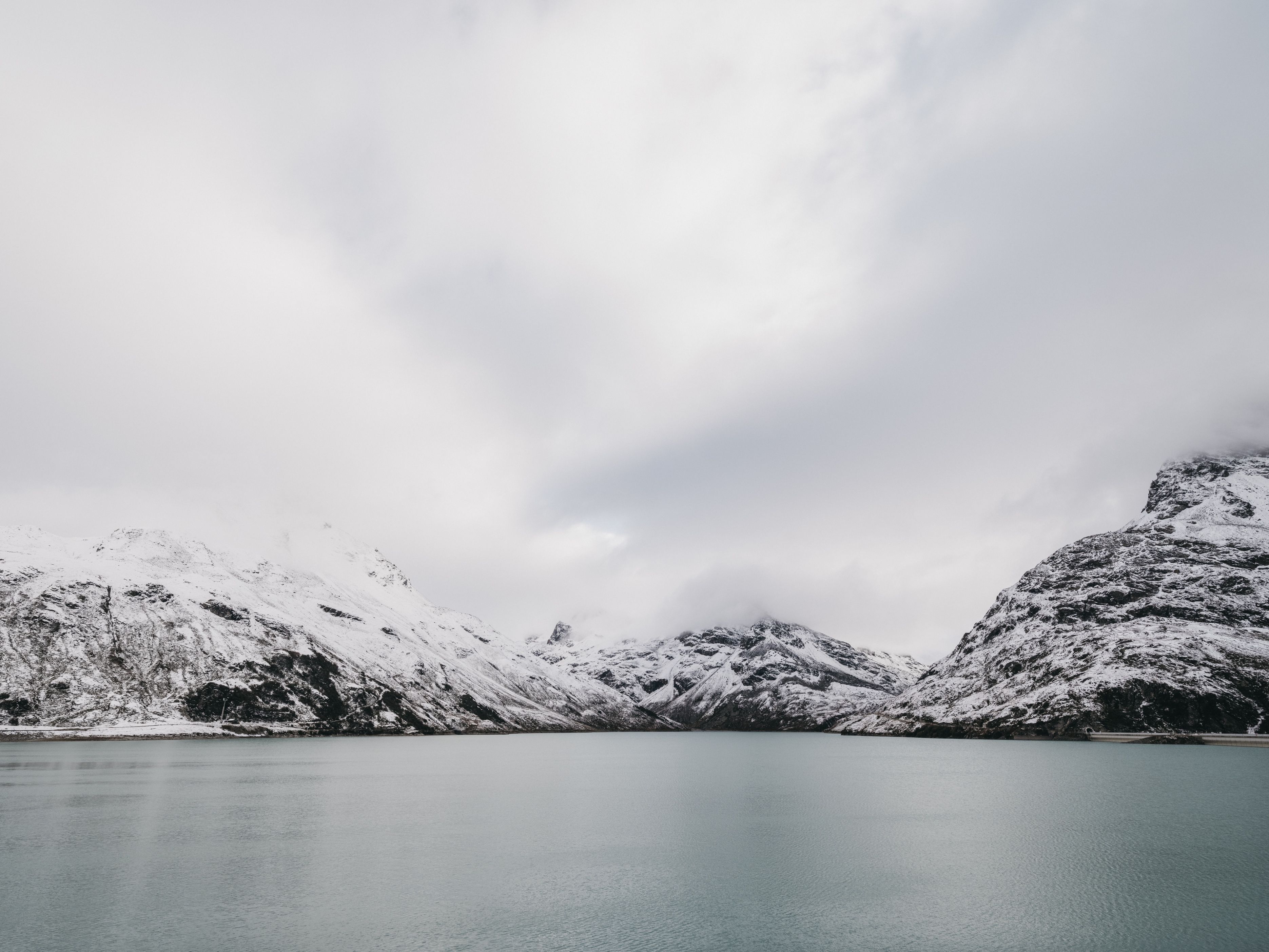 Een met sneeuw bedekte bergketen met een rustig meer op de voorgrond.