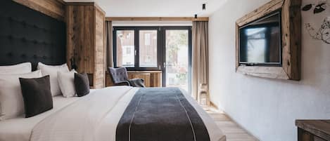 Un dormitorio moderno con una cama grande, cabecera de madera, un televisor montado en la pared y vistas al exterior a través de una ventana.