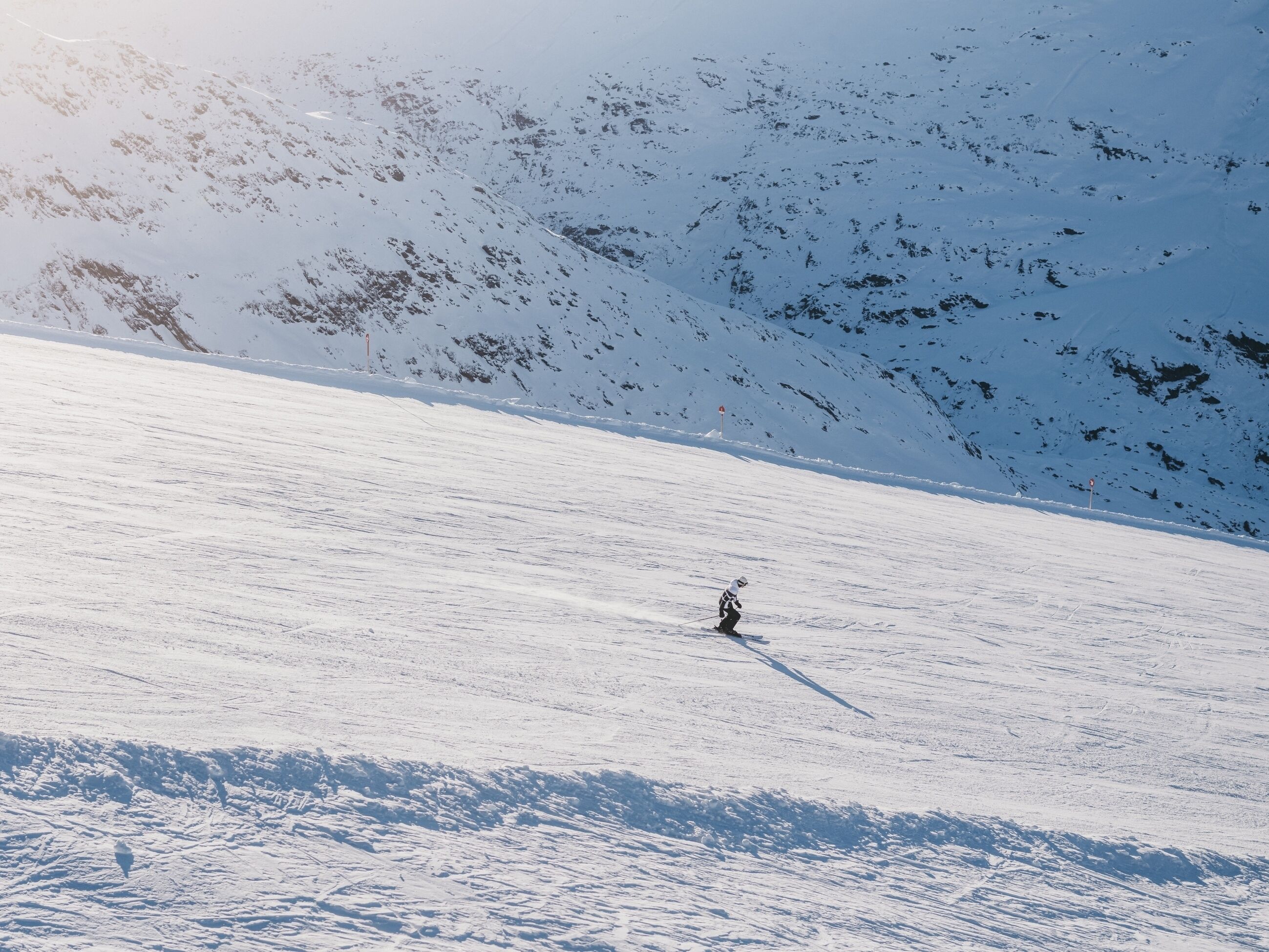 Pendio montuoso innevato con uno sciatore.