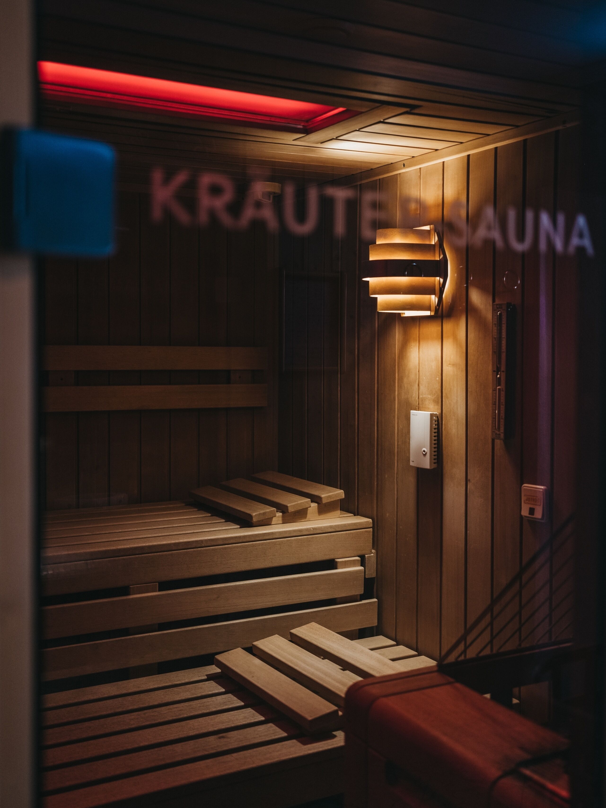 Ein Saunaraum mit Holzbänken und einer roten Lichtleiste.