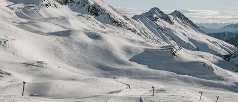A snow-covered ski slope with ski lifts and a clear sky.