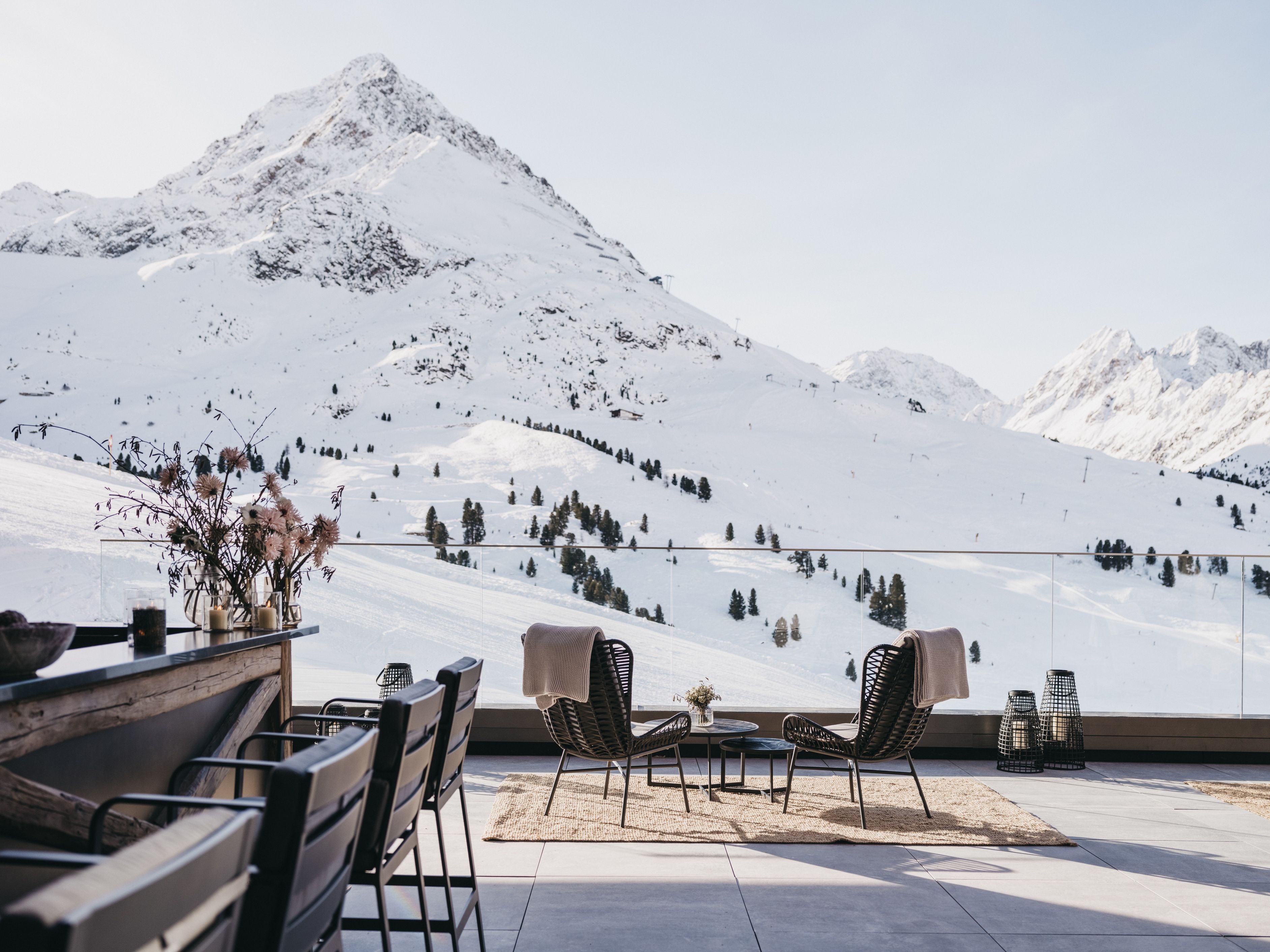 Eine Terrasse mit Sitzgelegenheiten mit Blick auf eine verschneite Berglandschaft.
