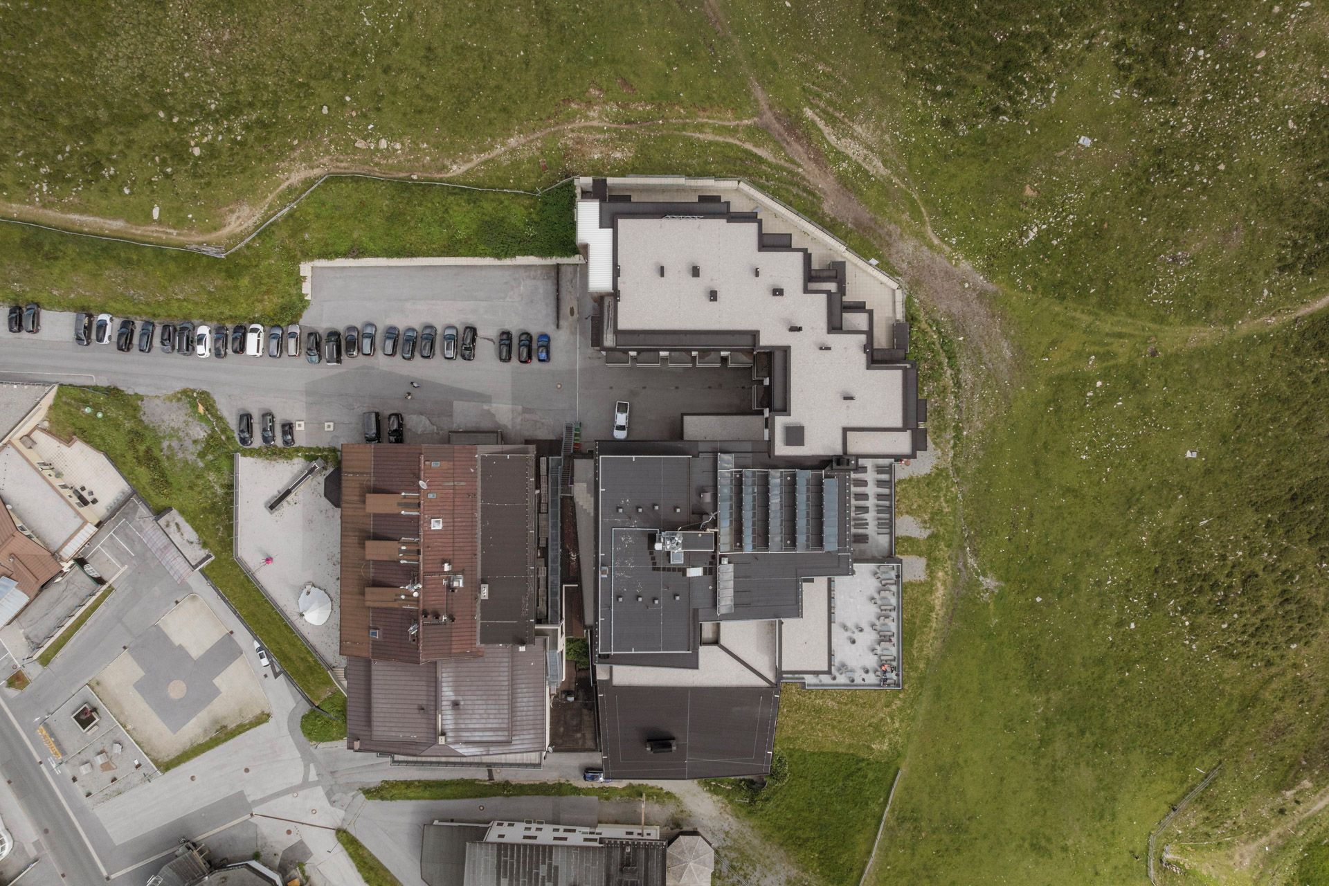 An aerial view of a building with multiple parking spaces, a central courtyard, and a mix of commercial and residential structures.