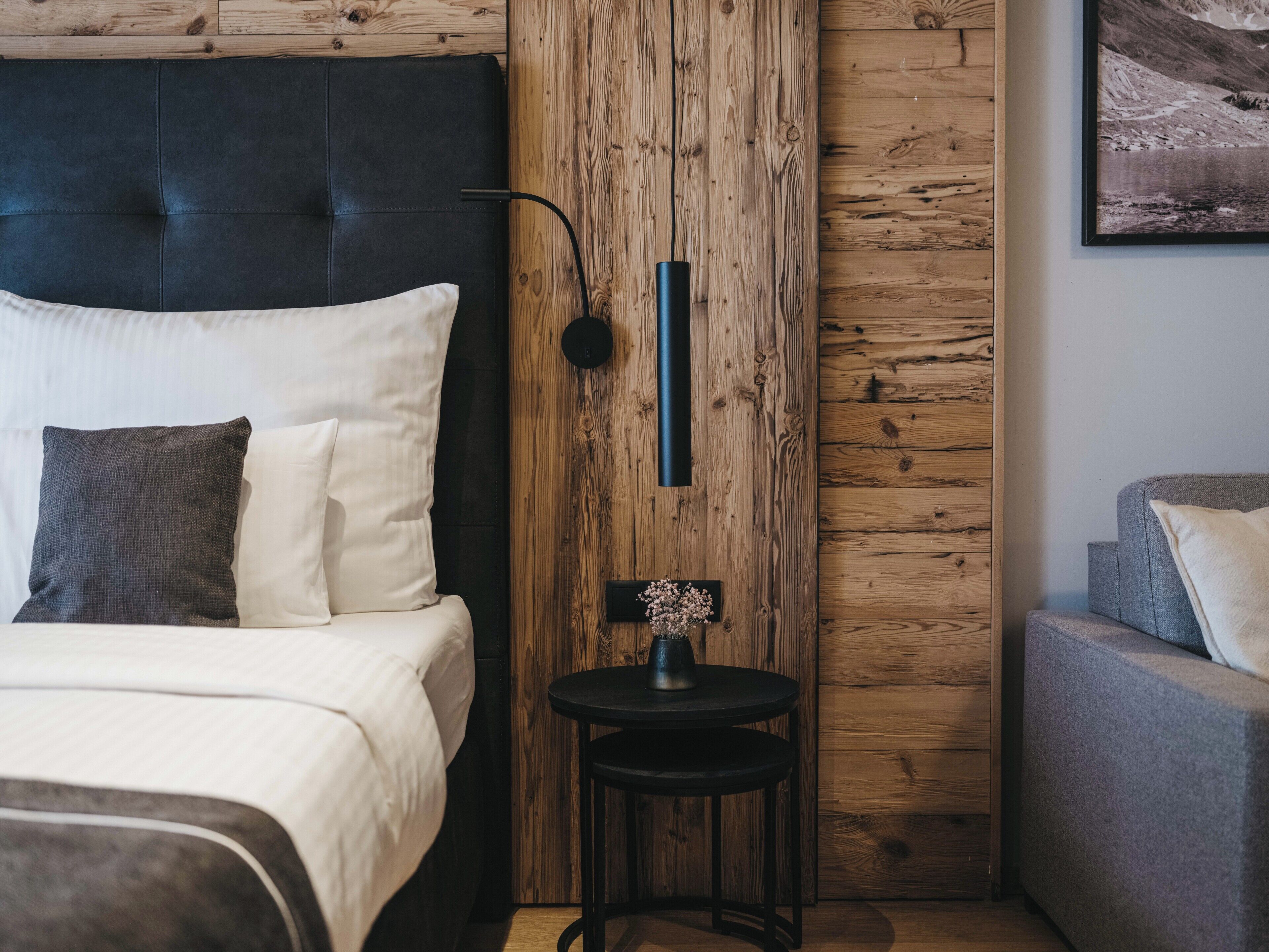 Een moderne slaapkamer met een bed, nachtkastje en een klein rond tafeltje met een vaas.