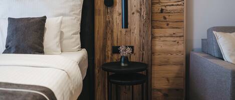 A modern bedroom with a bed, bedside table, and a small round table with a vase.
