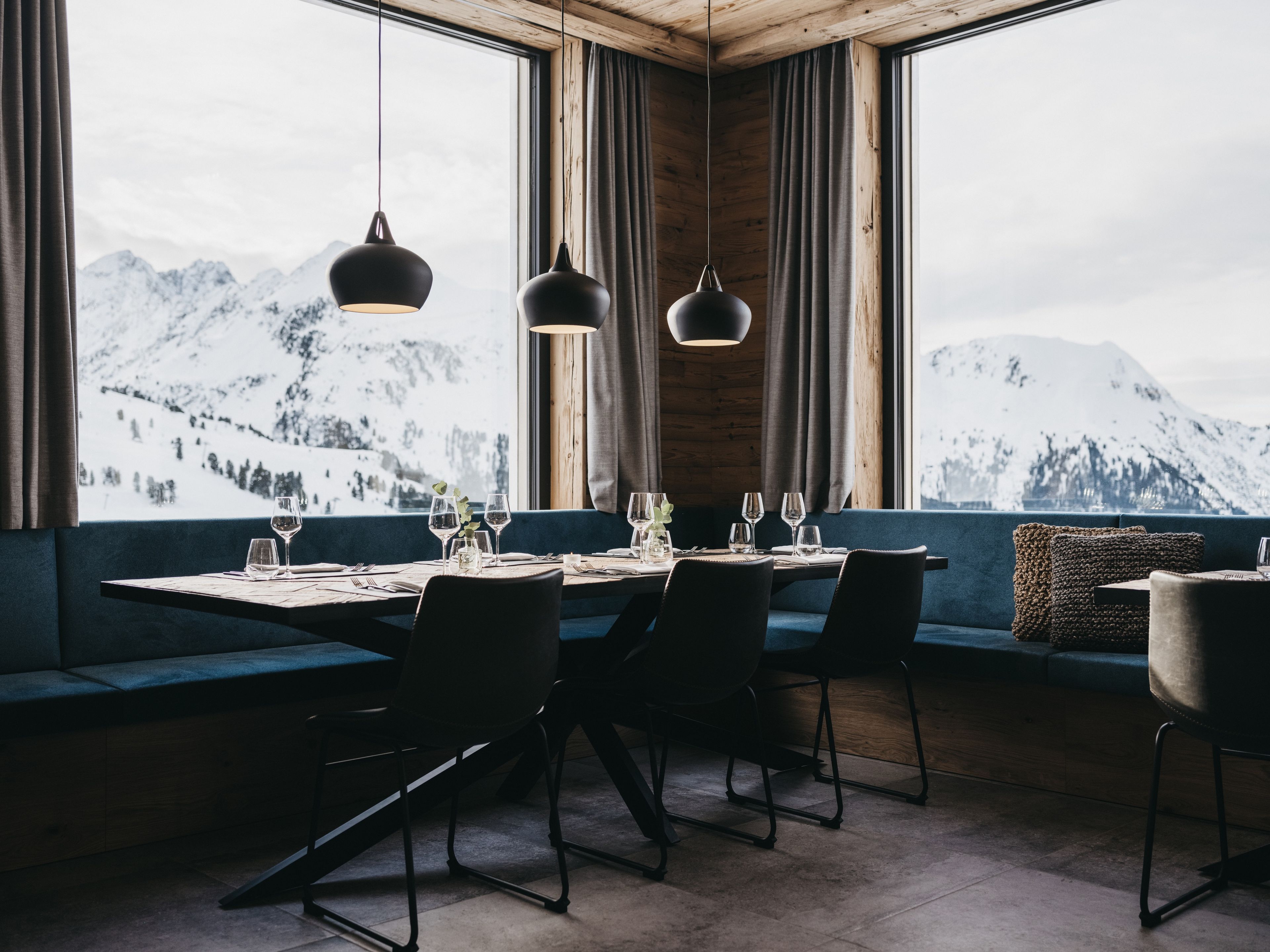 A dining area with a table set for four, large windows with a mountain view, and hanging pendant lights.