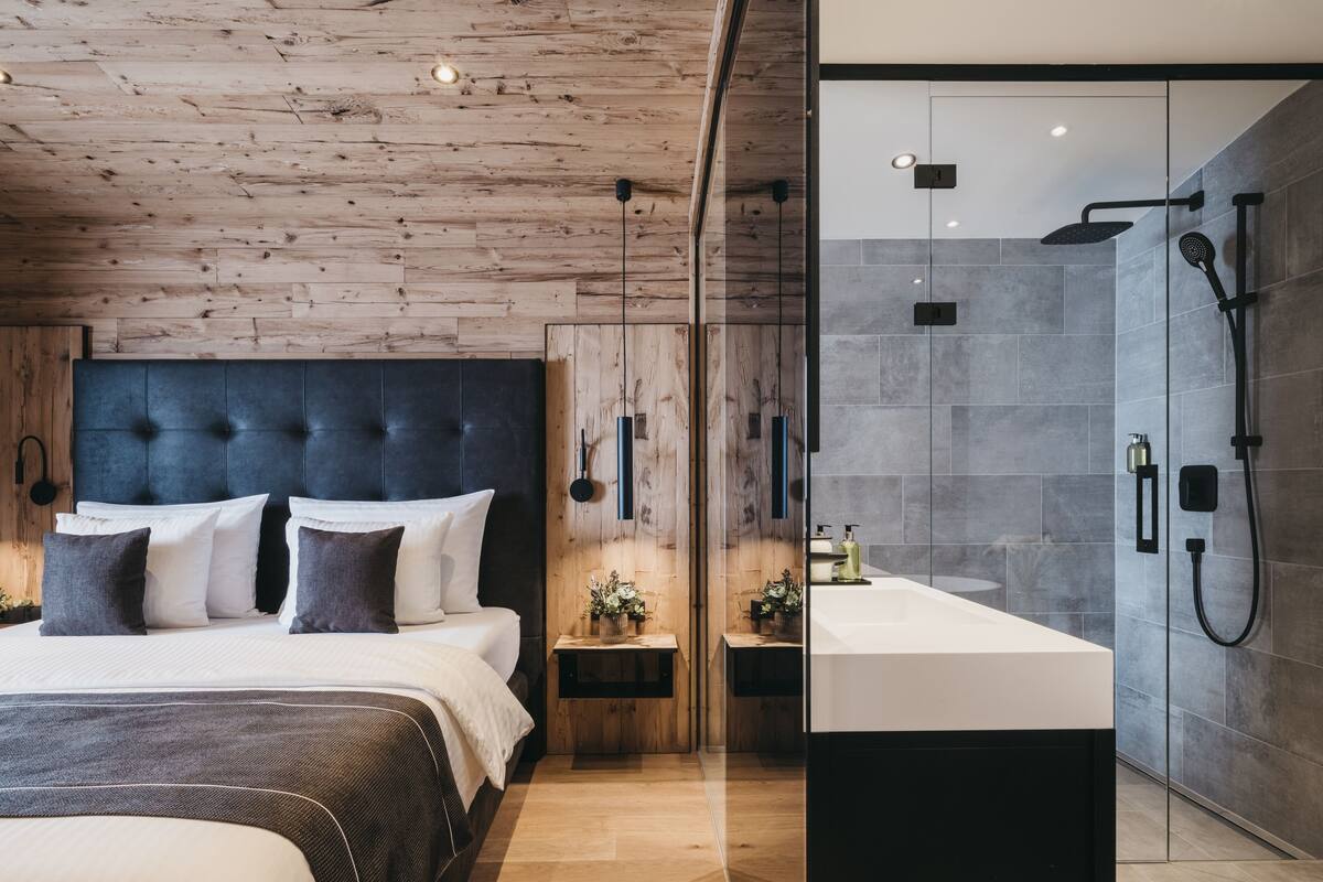 A modern bedroom with a wooden ceiling, a tufted headboard, and a large bed with multiple pillows.