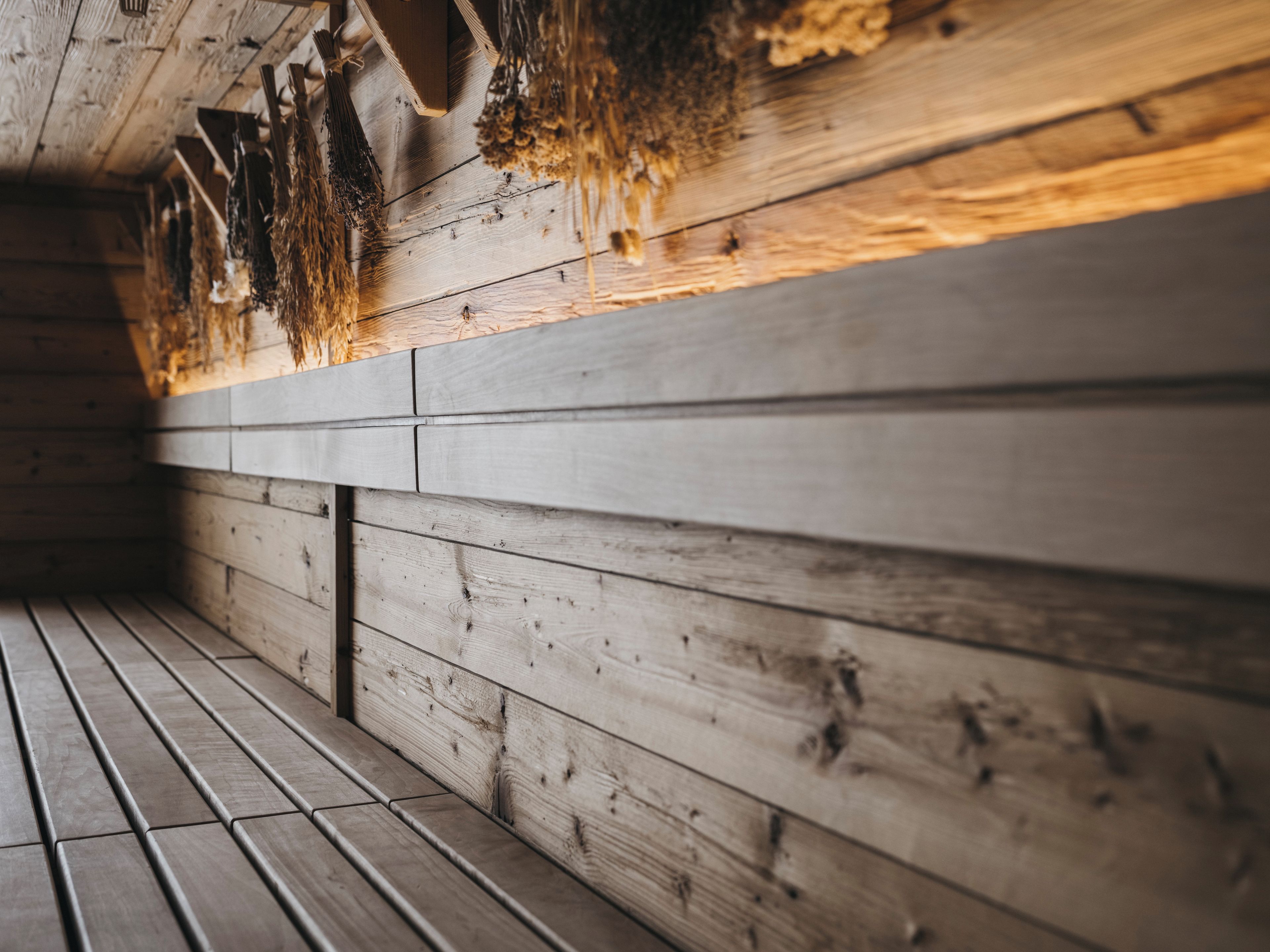 A wooden interior with a bench and a wall with a textured surface.