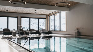 A spacious indoor swimming pool with clear views of a snowy mountain landscape through large windows. - VAYA Kühtai (Silz)