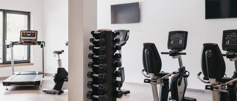 A gym with treadmills, an elliptical, and a dumbbell rack.